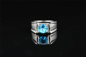 Primer plano de anillo plateado para hombre con gema azul redonda en fondo negro