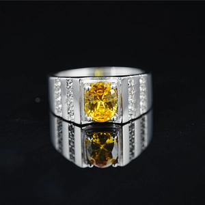 Anillo de acero de titanio con gema amarilla ovalada y circones sobre un fondo negro