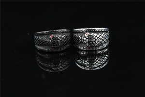 Macro detail of gothic snake rings with red zircon eyes and textured scale patterns
