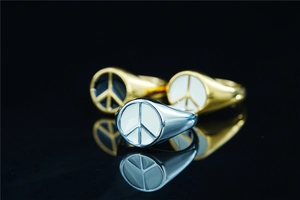Macro shot of gold and silver peace signet rings with enamel inlay on black background