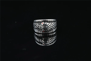 Detailed view of silver snake ring featuring red stone eyes and scale textures