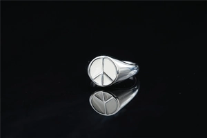 Macro detail of silver peace sign signet ring with white enamel on black reflection