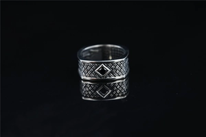 Detail of vintage woven patterns and black gemstone inlay on retro steel men's ring