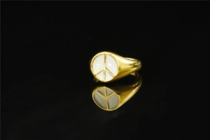 Macro detail of gold-tone peace sign ring with white enamel inlay and polished finish