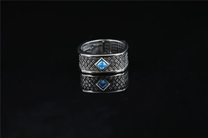 Macro detail of male silver ring with blue gemstone and S925 engraved woven band