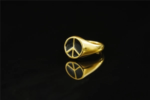 Detail of gold signet ring featuring a black Peace symbol with polished mirror reflections