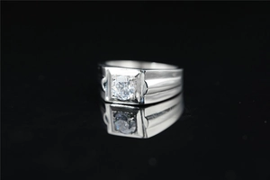 Macro shot of silver men's moissanite ring with square geometric band on black background