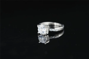 Macro-opname van een ronde moissanite-ring met vierpotige zetting op een zwarte achtergrond