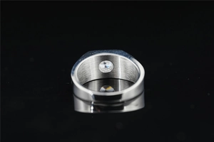Macro shot of silver men's ring with brushed metal texture and a central moissanite stone