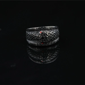 Vintage gothic snake ring with scales and red gemstones on black mirror surface