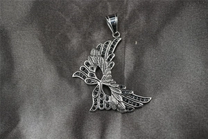Macro shot of vintage silver wing pendant with detailed feathers and black zircon stones