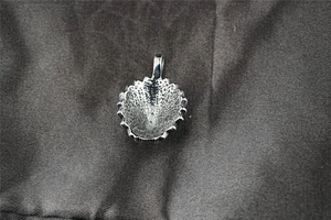 Détail macro du pendentif chef indien argenté montrant la texture alvéolée et dentelée