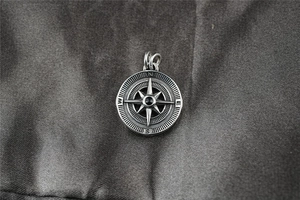 Détail macro d'un pendentif boussole en argent vintage avec gravure N E S W et pierre noire