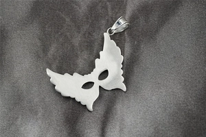 Detailed macro view of a silver gothic mask pendant with wings and brushed metal finish