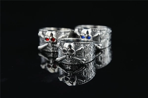 Detailed trio of punk skull rings with red and blue gemstone eyes and aged silver finish