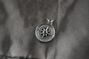 Gros plan d'un pendentif boussole rétro avec étoile à huit branches sur tissu gris chiné