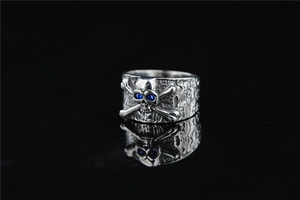 Detail of vintage punk skull ring with blue rhinestone eyes and textured silver finish