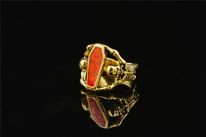 Gothic gold coffin ring featuring red accents and detailed skull carvings on the side