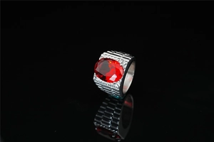 Close-up of a men's titanium steel ring with a large oval red ruby zircon and stepped texture