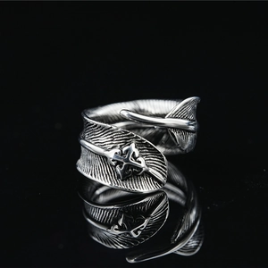 Retro oxidized silver feather ring with cross detail on a black reflective surface