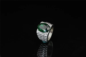 Detail of a men's silver steel ring with a large faceted oval green gemstone and textured band