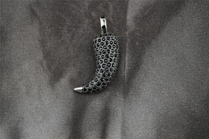 Macro shot of hip hop chili pepper pendant featuring pavé set black crystals on silver metal