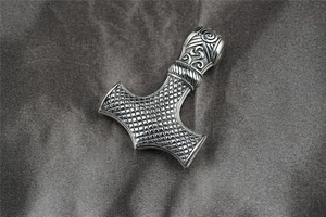 Gros plan détaillé du pendentif marteau de Thor viking en argent sur tissu en satin gris