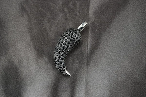 Detailed macro view of horn pendant with pavé set black stones on textured grey background