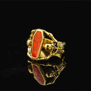 Gothic gold coffin ring with red glaze and skull reliefs on mirror black background
