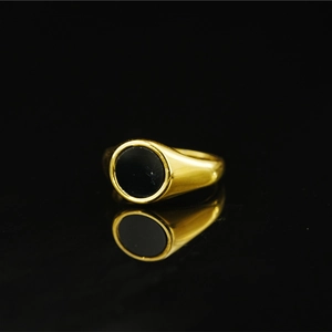 Vintage golden signet ring with black round inlay and mirror reflection on black background