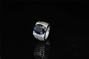 Macro shot of silver titanium ring with large oval blue gemstone and link textures