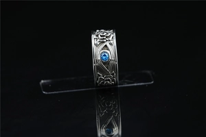 Macro shot of retro steel ring featuring rose relief and a bright blue gemstone inlay