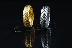 Macro detail of wide tire-tread textured metal rings in gold and silver finishes