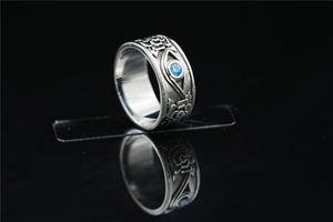 Detail of vintage steel ring featuring rose relief and a centered blue zircon stone