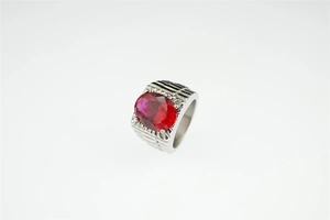 Macro shot of men's titanium ring with red gemstone and grooved industrial band