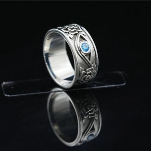 Vintage steel ring with rose embossing, eye symbol and blue gemstone on black reflective base