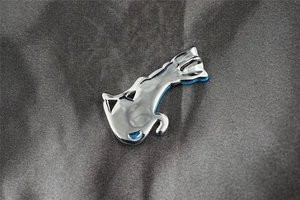 Detailaufnahme eines silbernen Walanhängers mit blauen Emailleflossen auf Stoff