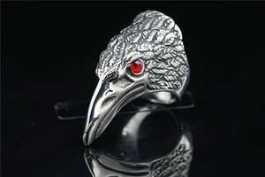 Macro detail of gothic eagle head ring with red gem eyes and carved silver feathers