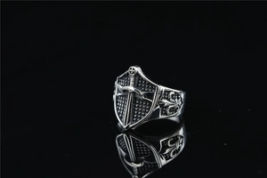 Macro view of medieval shield ring with cross and sword engraving on vintage titanium steel