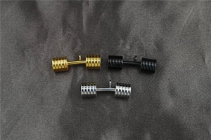 Detailed macro view of solid dumbbell pendants in polished gold, black, and silver finishes