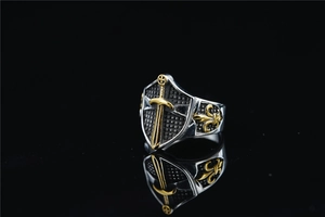 Macro detail of medieval shield ring with golden dagger and fleur-de-lis engravings