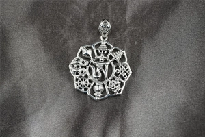 Makroaufnahme von silbernem Titanstahl-Anhänger mit Om-Symbol und buddhistischen Mustern