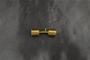 Detailed close-up of a solid gold dumbbell pendant with a polished metallic finish