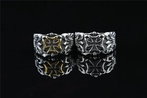 Close-up of retro hollow iron cross rings in silver and gold tone on black reflective base