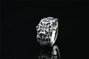 Detailed close-up of retro silver cross ring with Gothic floral engraving and mirror reflection