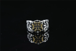 Close-up of vintage biker ring featuring gold cross relief on textured silver band