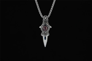 Detail of gothic dragon claw pendant with red gemstone and silver textured scales