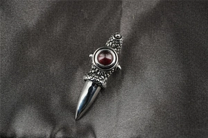 Detailed macro view of a silver dragon sword pendant with a red gemstone on silk