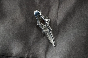 Macro shot of punk style dragon claw pendant with red gemstone on grey silk fabric