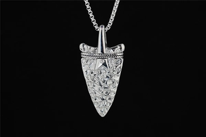 Detailed close-up of textured silver arrowhead pendant with hammered finish and box chain